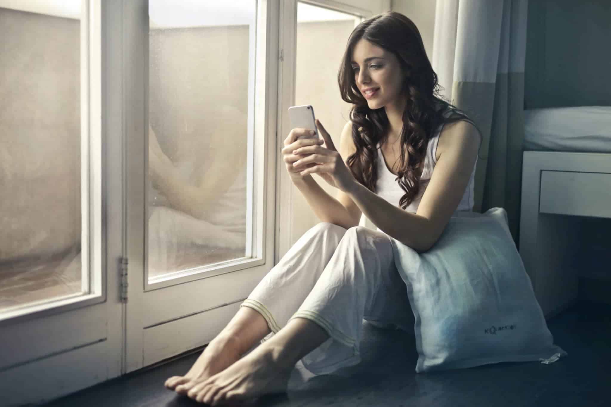 woman sitting beside window holding phone 915051 scaled 1